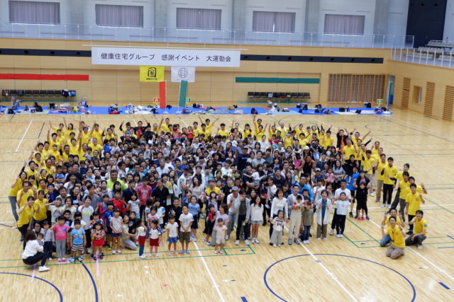 健康住宅グループのお客様感謝イベント大運動会で、家族連れ約300名が体育館に集まり笑顔で記念撮影する様子