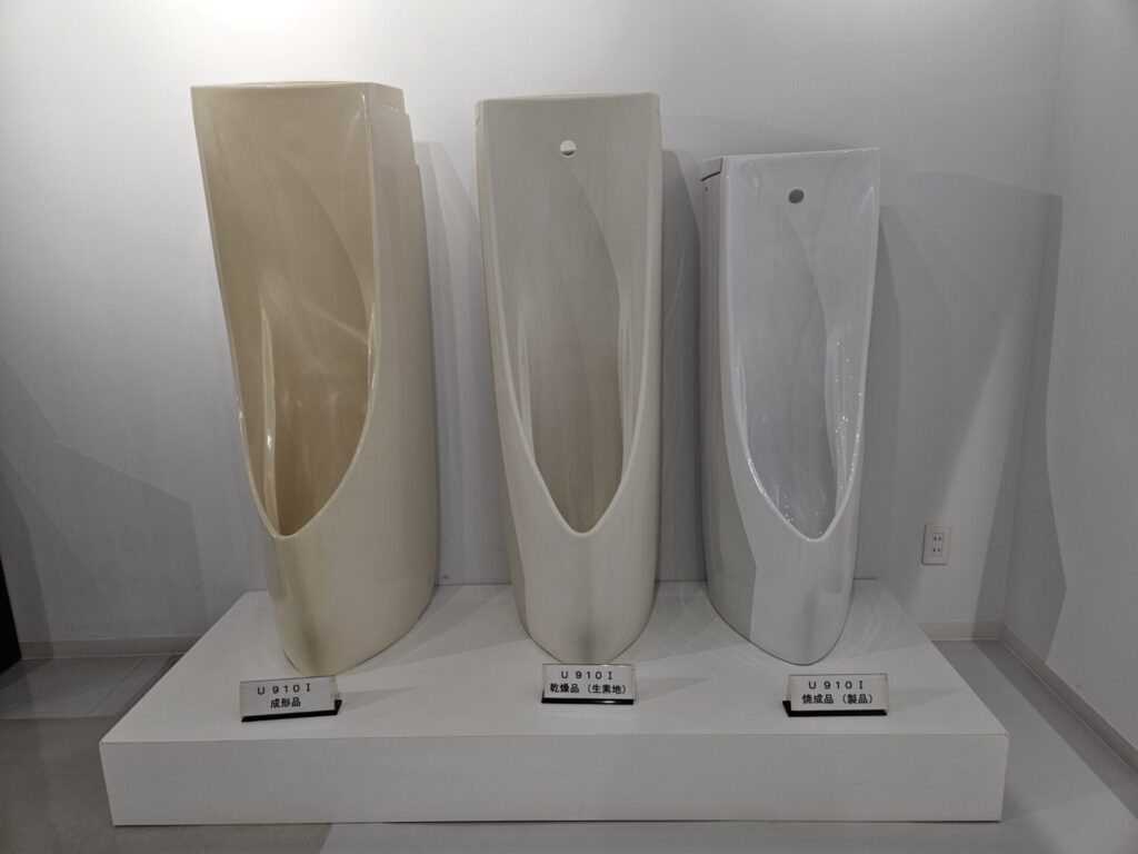 衛生陶器の成形品・乾燥品・焼成品を並べた工程比較展示。製造過程による変化が分かる展示