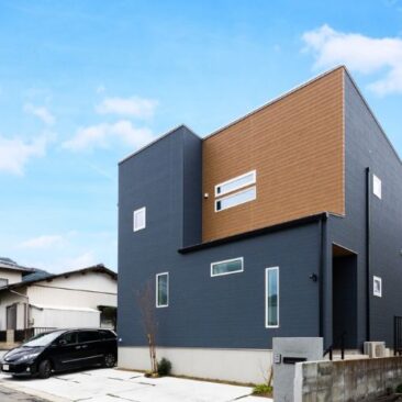 ネイビーと木目を組み合わせた外観が印象的な、吹抜けとスキップフロアのある二階建て住宅