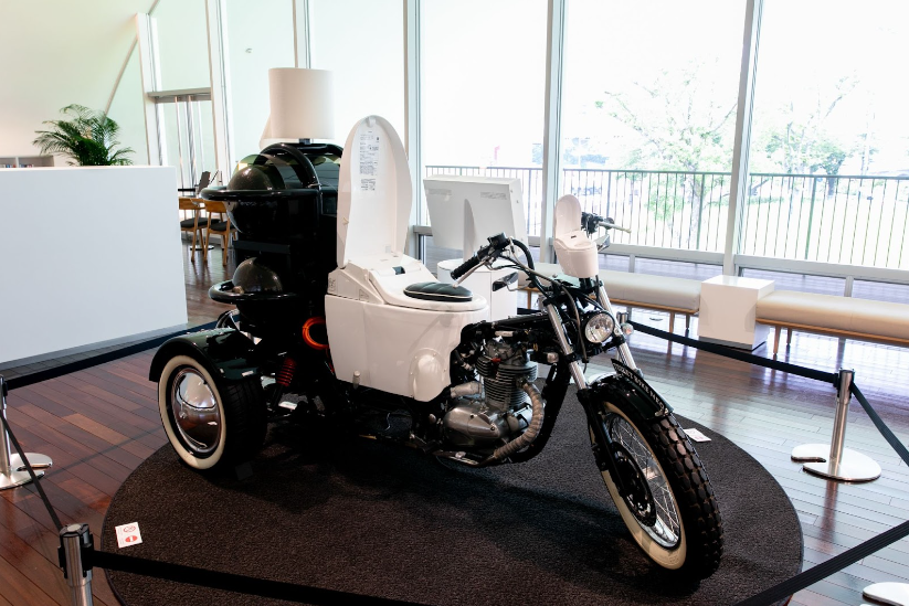 環境PRのために制作されたトイレバイクネオ。便器が運転席になったユニークな展示物