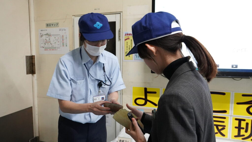 制震ダンパーの要となる高減衰ゴムについて、実物を使って説明を受ける取材の様子