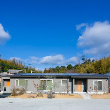 自然に囲まれた敷地に建つ、横に広がる平屋の二世帯住宅の外観