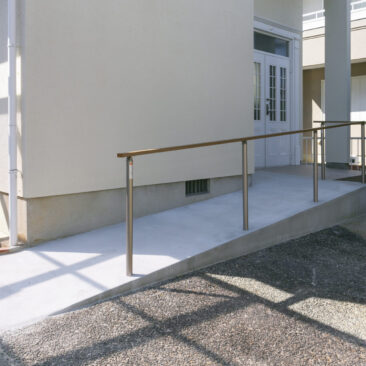 玄関まで緩やかに続く、モルタル刷毛引き仕上げのスロープアプローチ