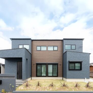 グレーと木目を組み合わせた、左右対称の重厚感ある二階建て住宅の外観