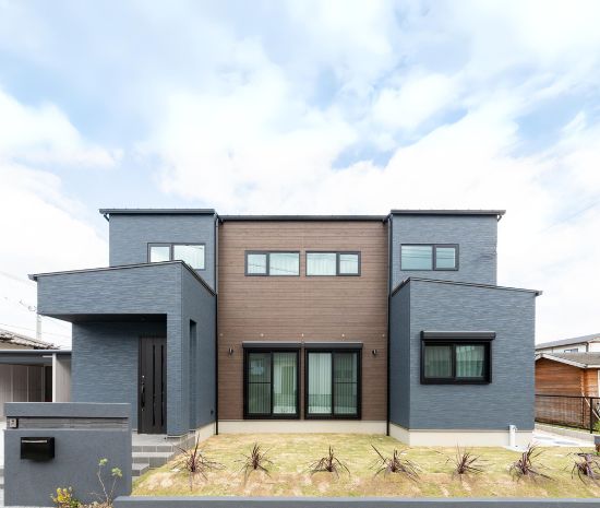 グレーと木目を組み合わせた、左右対称の重厚感ある二階建て住宅の外観