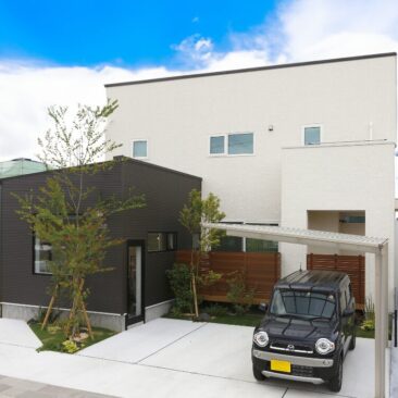 白とダークカラーを組み合わせた、店舗併用のシンプルモダンな二階建て住宅外観