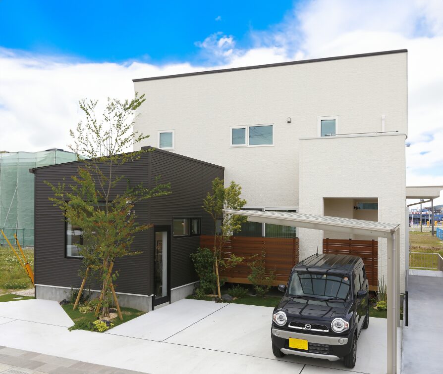 白とダークカラーを組み合わせた、店舗併用のシンプルモダンな二階建て住宅外観