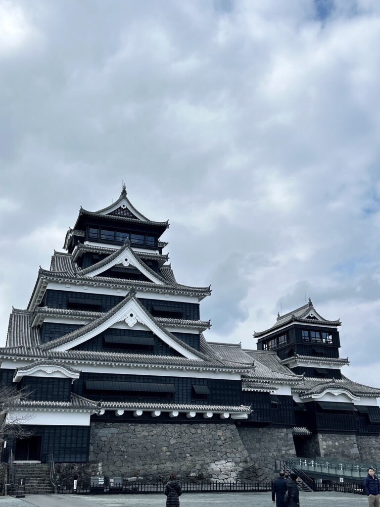 熊本地震から復興を遂げた熊本城天守閣の外観。美しい瓦屋根と石垣、青空に映える日本の名城の風景。