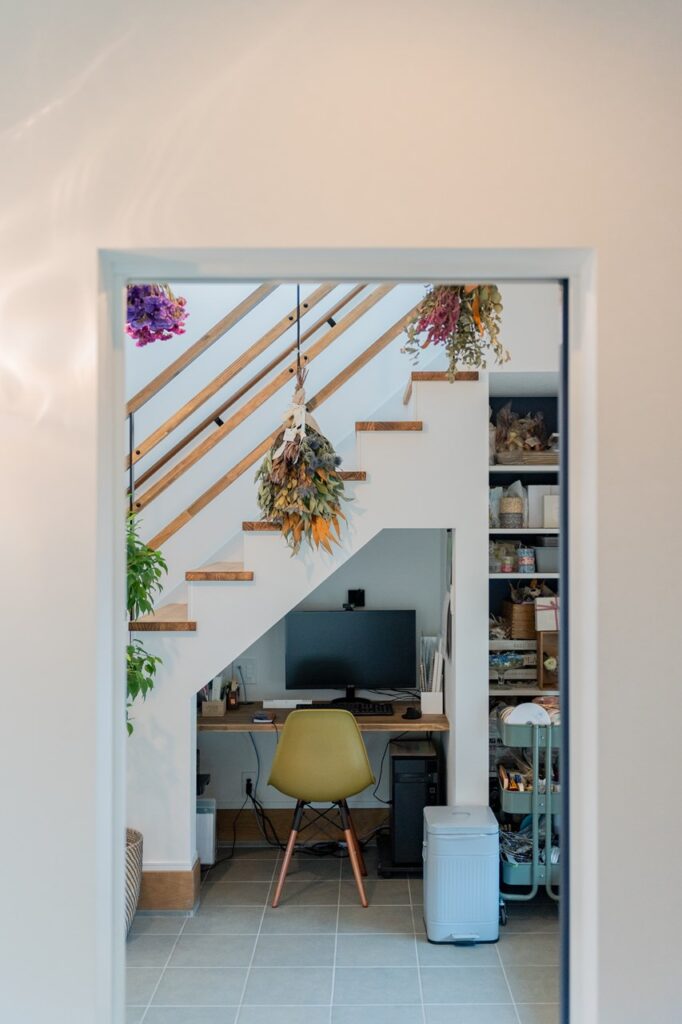 階段下のデッドスペースを有効活用した造作ワークスペース。ドライフラワーが飾られた、集中できる趣味や仕事のためのデスクコーナー。