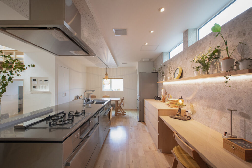 入居半年のオーナー様邸キッチン。ステンレス天板のペニンシュラキッチンと、センス良く飾られた飾り棚がある明るいLDK空間。