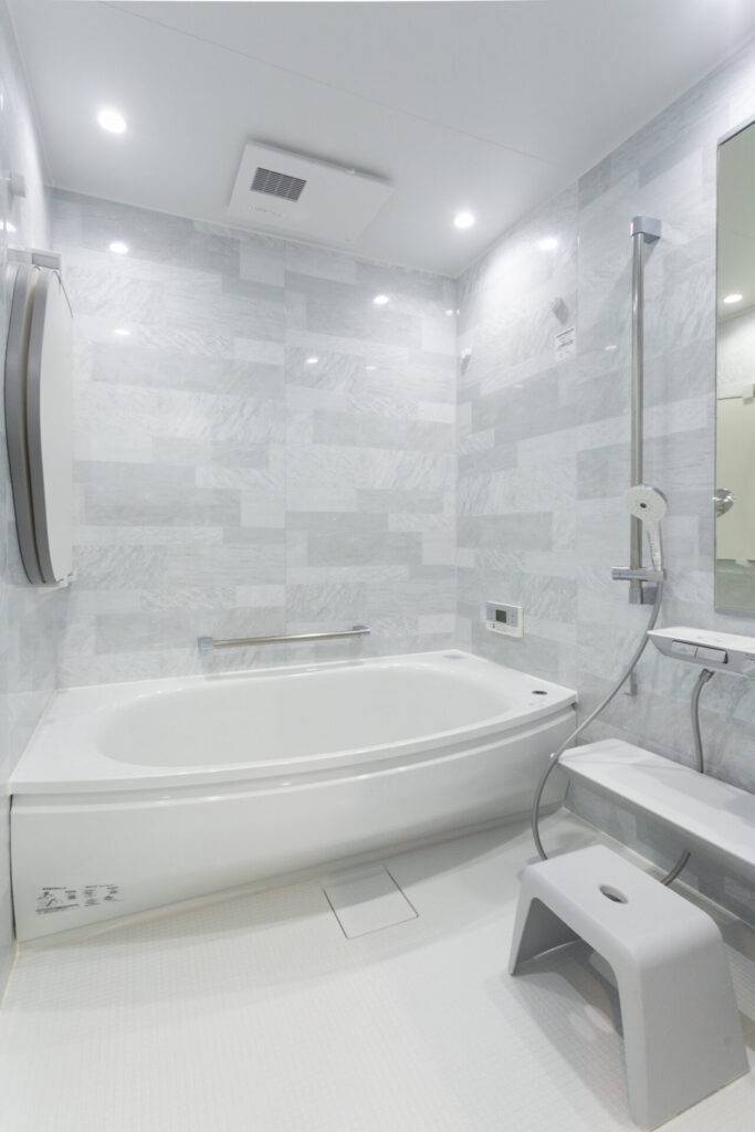 TOTOの「ほっカラリ床」と「床ワイパー洗浄」を搭載したシステムバス。白を基調とした清潔感のある広々としたバスルーム空間。