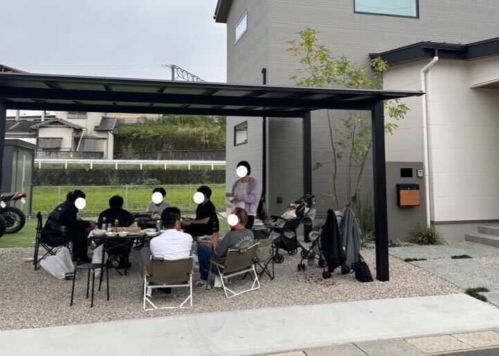 オーナー様邸のカーポート下で開催された1周年記念BBQパーティー。ご家族やご友人が集まり、お庭で楽しく食事を囲む様子。