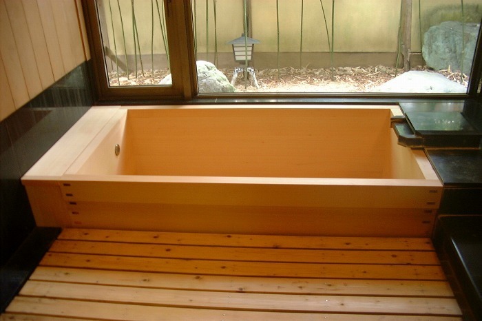 坪庭を望む高級感あふれる檜風呂(ひのきぶろ)。御影石の洗い場と天然木の浴槽が調和した、和モダンな浴室デザイン。