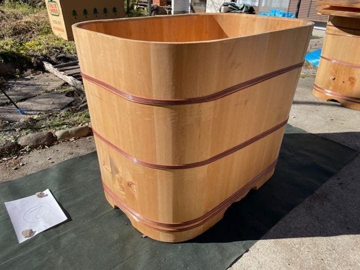 職人の手で丁寧に作られた、木目が美しいオーバル型の木風呂浴槽。銅のタガで締められた伝統的な工芸美を感じる仕上がり。