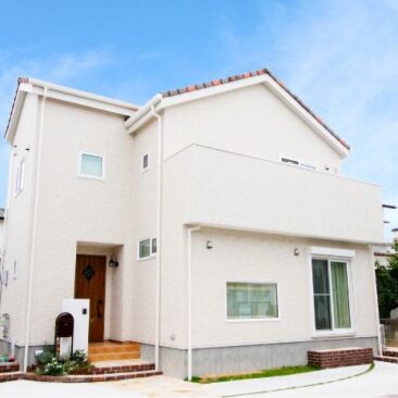 白い外壁とやわらかな屋根形状が印象的な、家族向け二階建て住宅の外観