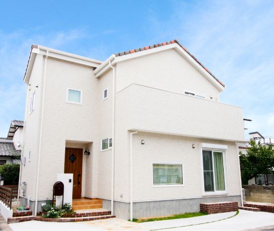 白い外壁とやわらかな屋根形状が印象的な、家族向け二階建て住宅の外観