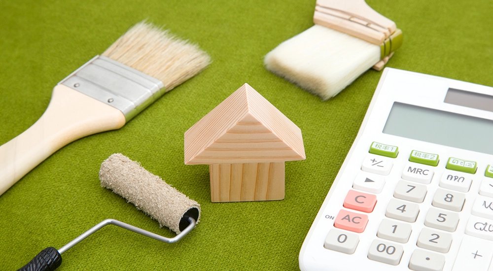 リノベーションの費用や計画をイメージさせる家の模型と道具